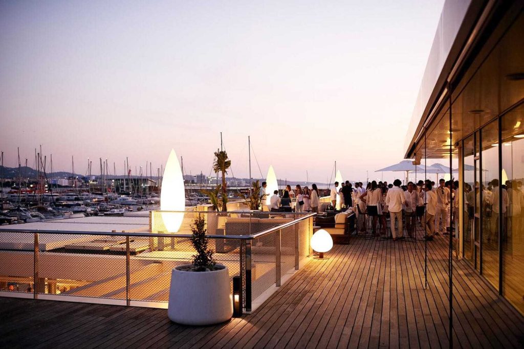 Gente de noche en la terraza con vistas al puerto