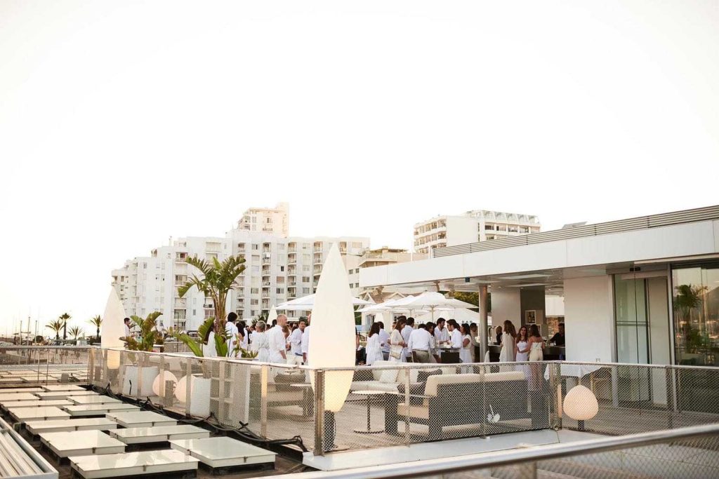 Gente al atardecer en la terraza con vistas al puerto