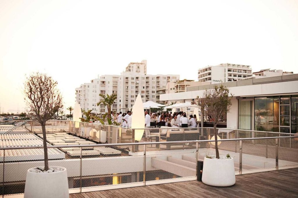 Gente al atardecer en la terraza con vistas al puerto